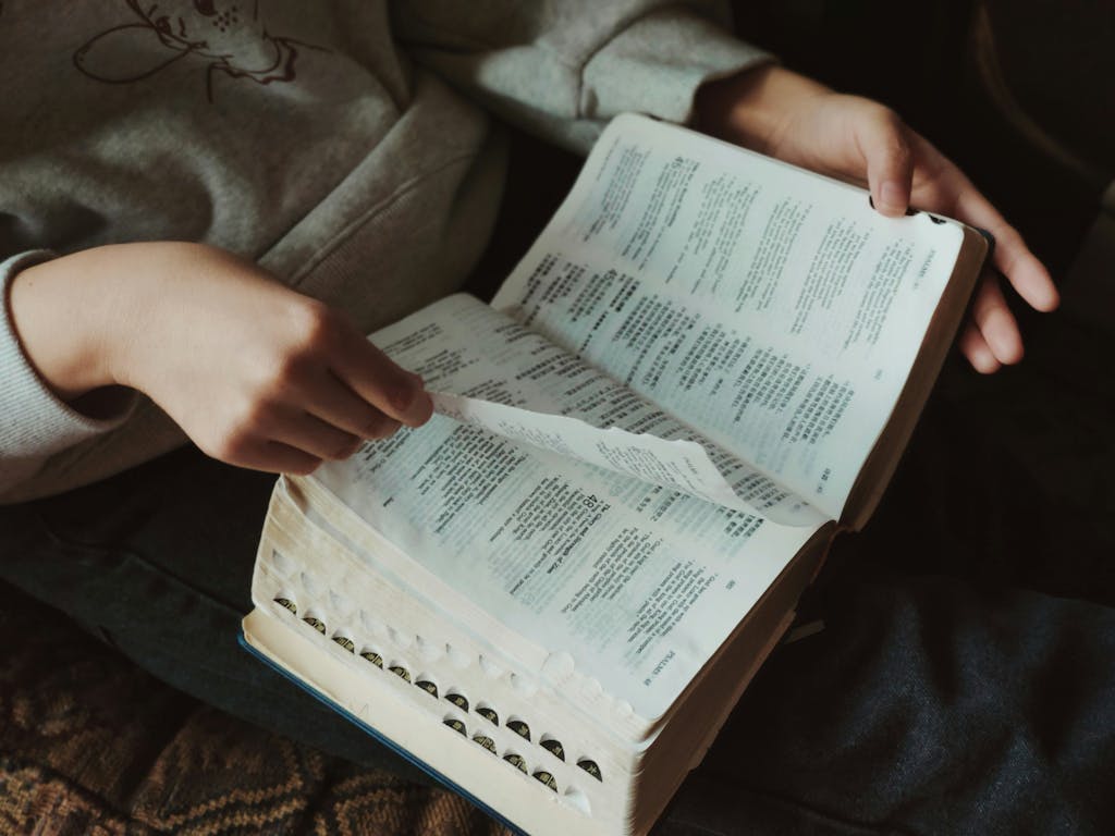 A person flipping through pages of a book, capturing a moment of thoughtful reading indoors.