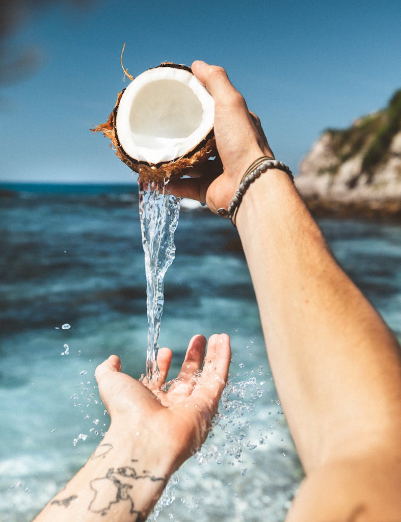 A refreshing splash of coconut water being poured by the seaside.