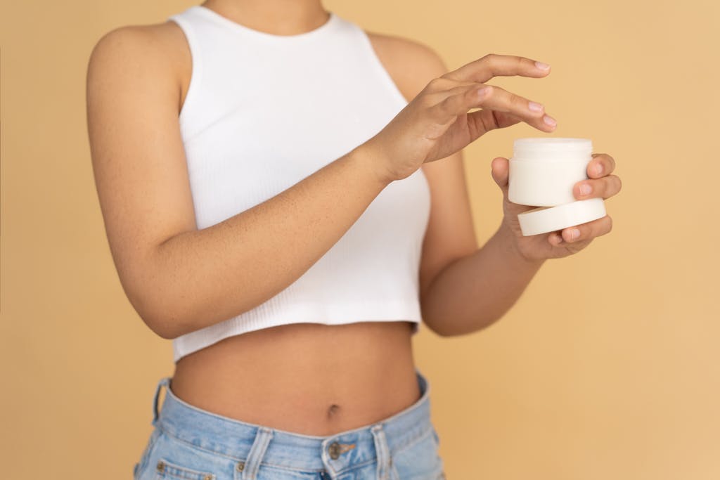 Close-up of a young woman applying face cream, emphasizing healthy skin and lifestyle.