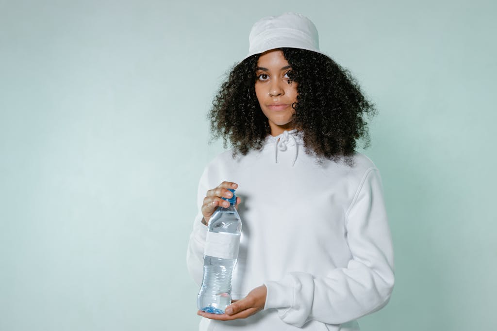 Woman in white hoodie holds a bottled water, conveying a fresh and casual vibe.