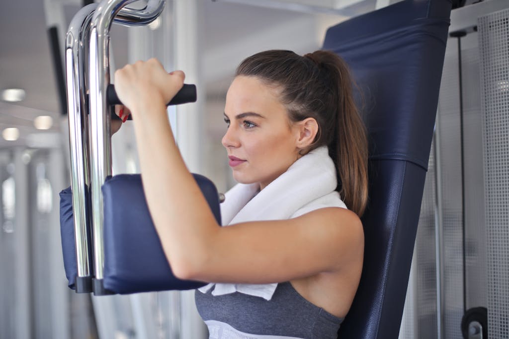 Young woman working out on a chest press machine in the gym, showing strength and determination.